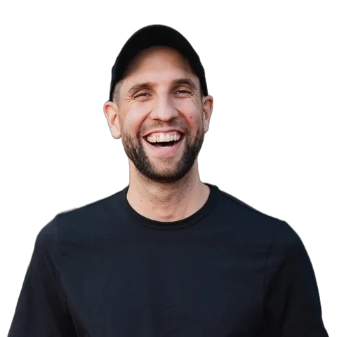 Porträt von Patrick Reymann mit Kappe, lachend, in schwarzem T-Shirt.